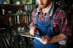 Modern repairman in uniform working on touchpad