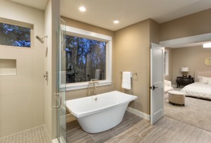 Master bath with tile floor, fancy cabinets, large mirror, and bathtub