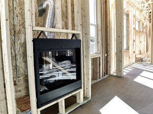 Framed home showing installation of a gas fireplace with vent